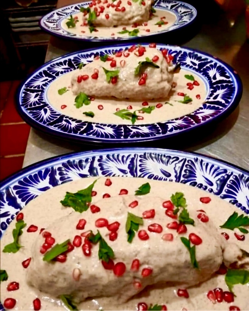 Chiles en nogada con salsa de nogada, granada y perejil en platos de talavera